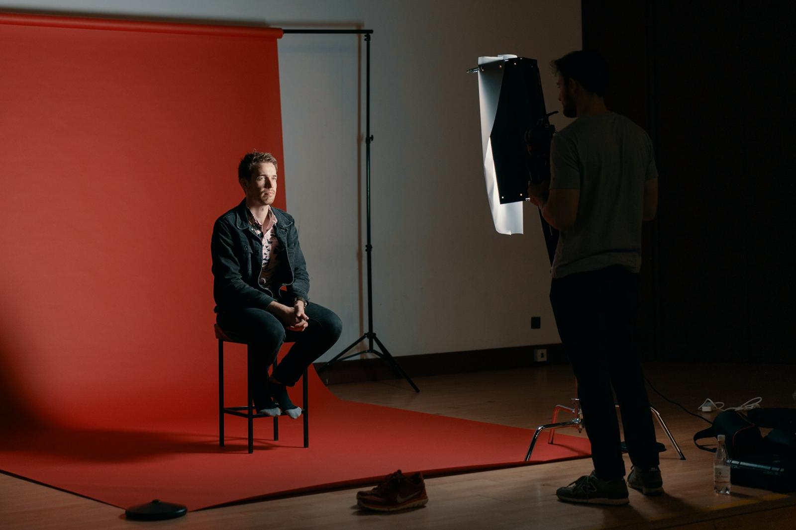 Portrettfotografering mot rød bakgrunn i studio